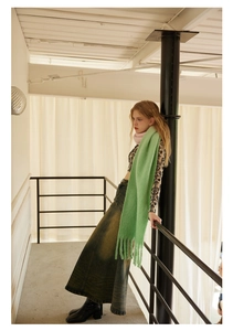 Detail of soft green wool blend scarf featuring elegant fringe ends for winter