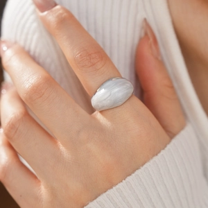 Macro shot of minimalist marble resin statement ring on a white knitted sleeve