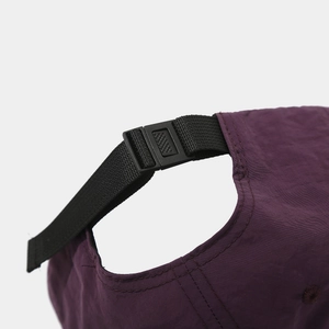 Detail of adjustable black buckle and woven strap on dark purple nylon baseball cap