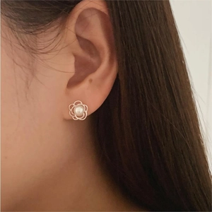 Close-up of minimalist silver flower pearl earrings worn on ear with elegant style