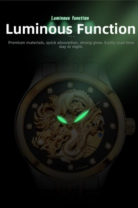 Détail des aiguilles lumineuses et du relief de dragon doré sur une montre automatique