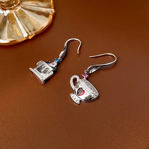 Close-up of asymmetrical teacup earrings with colorful zircons and silver finish