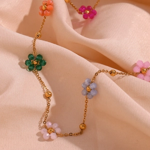 Macro detail of colorful beaded flower necklace with gold chain on silk background