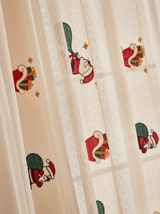 Detail showing Santa Claus embroidery on semi-sheer beige Christmas lace curtain fabric