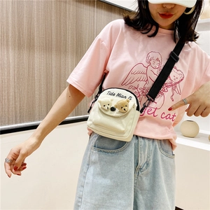 Detail of white canvas crossbody bag featuring 3D plush bear charms and brand text