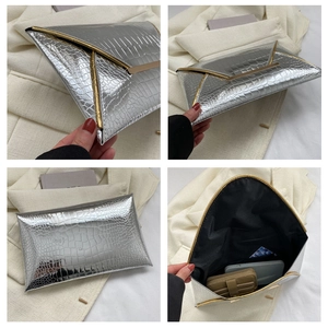 Detail view of silver crocodile embossed envelope clutch with elegant gold metal trim