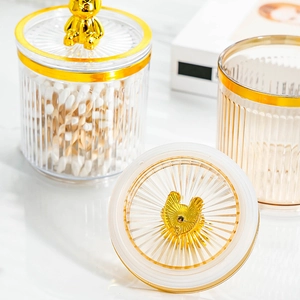 Detail of food-grade storage jar with golden bear lid showing cotton swabs and clear acrylic