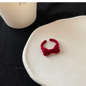 Detailed close-up of a vintage dark red flocked bow open ring on a ceramic tray
