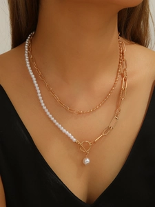 Detail of layered gold beaded chain necklace with pearls and OT toggle clasp on model