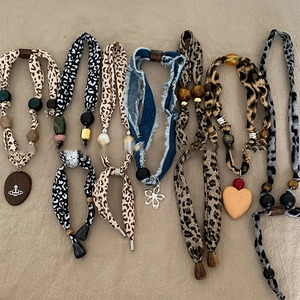 Flat lay of bohemian fabric necklaces with leopard print, denim heart, and wooden beads