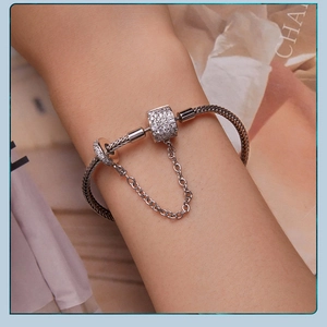 Detailed view of silver snake chain bracelet with pave zircon charm on female wrist