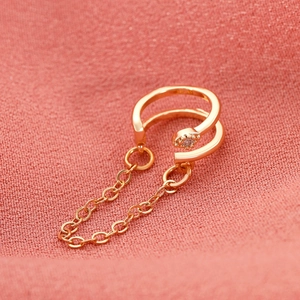 Λεπτομέρεια από χρυσό σκουλαρίκι ear cuff με αλυσίδες και λαμπερή πέτρα ζιργκόν