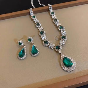 Vintage jewelry set featuring emerald pear-shaped necklace and drop earrings on tray