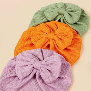 Knitted baby turban hats with large bows in light green, orange, and purple waffle fabric