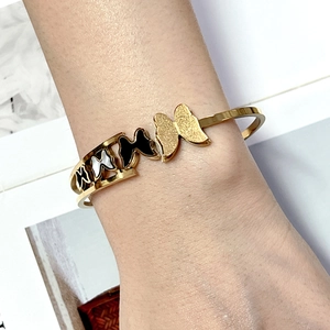 Minimalist gold butterfly cuff bracelet with black enamel and white shell on model wrist