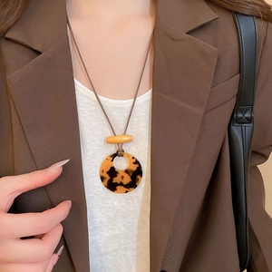 Close-up of leopard resin ring and wood bead pendant necklace on a brown suit
