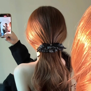 Rear view of black and white checkered hair scrunchie with a delicate black bow decoration