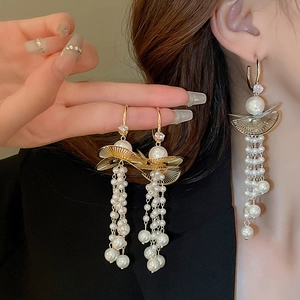 Detail of fan-shaped pearl tassel earrings with zircon studs shown on a model