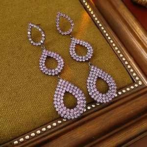 Detail of lavender crystal tiered teardrop earrings on a vintage green velvet background