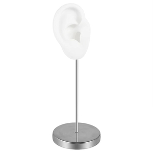 Detail of white silicone ear model on a silver metal stand for jewelry display