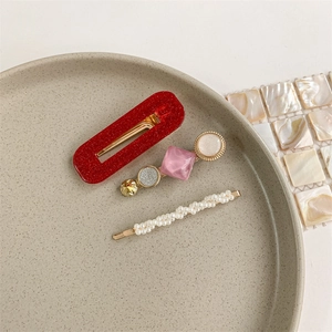 Detailed shot of three hair clips featuring red glitter, pink acrylic, and white pearls