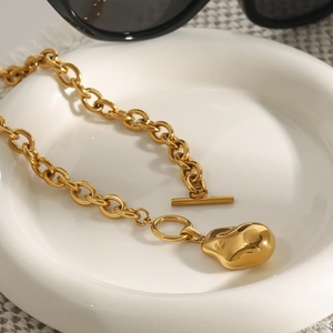 Dettaglio pendente a goccia d'oro con catena a O e chiusura a T in vassoio ceramico