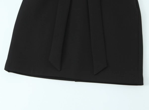 Detailaufnahme des überlappenden Saums an einem schwarzen Kleid mit Stickerei