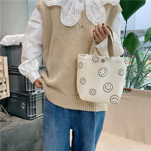 Detail of white corduroy tote bag with smiley pattern and magnetic closure texture