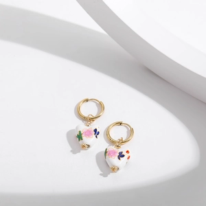Detailed shot of heart-shaped blue and white porcelain earrings with enamel floral patterns