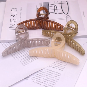 Close-up of four assorted large claw clips in transparent and matte finishes on a magazine
