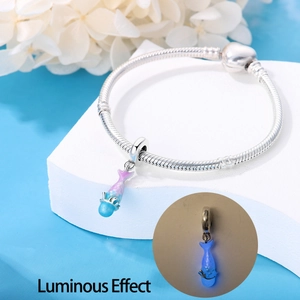 Detailed view of silver snake chain bracelet with a blue-pink luminous whale charm