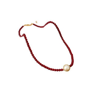 Gold plated necklace with red beads and white pearl pendant on a white background