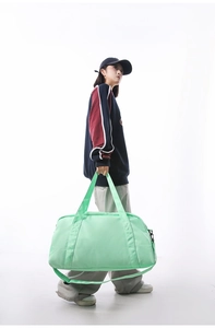 Full view of light green large capacity travel duffle bag carried by female model