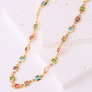 Detail of 18K gold-plated chain with square colorful zircons draped on a white stone