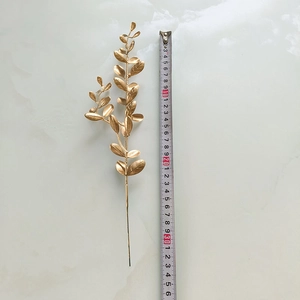 Détail d'une branche de feuille dorée artificielle de 34cm avec échelle de mesure précise