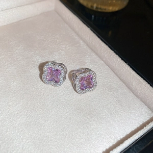 Macro view of pink zircon flower stud earrings in silver setting on white jewelry tray