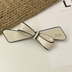 Detail of cream bow hair clip with black piping and gold La France lettering