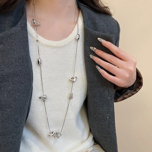 Irregular square pendant necklace worn with a grey blazer for a modern Y2K style
