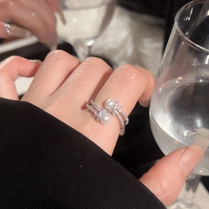 Detail of silver double pearl ring with zircon accents worn in a formal evening setting