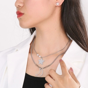 Detailed view of silver double-layer necklace with star and moon pendants and stud earrings