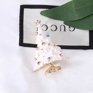 Close-up of white enamel Christmas tree brooch with colorful rhinestones and gold star