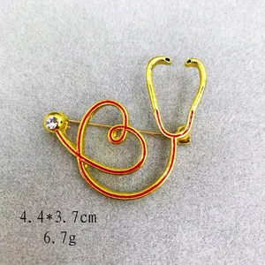 Detail of stethoscope brooch with red enamel and rhinestone on grey felt background