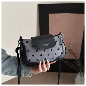Detailed view of the gray polka dot crossbody bag with a black leather flap and metallic buckle