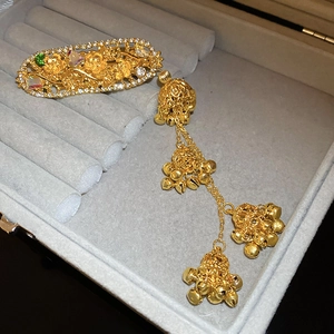Detailed shot of ethnic gold flower hair clip with diamond tassel and bell pendants