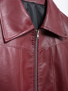 Detail shot of a burgundy faux leather jacket featuring contrast white stitching and metal zipper
