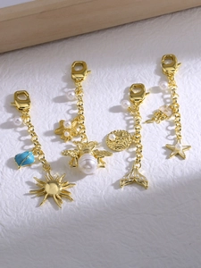 Macro detail of gold-plated sun and bee pendants with pearls and blue enamel charms