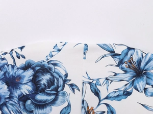 Macro view of blue floral print on white fabric with precision stitching detail