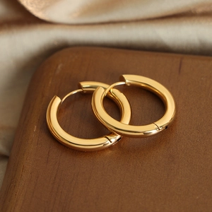 Polished gold geometric hoop earrings on luxury champagne silk and dark wood