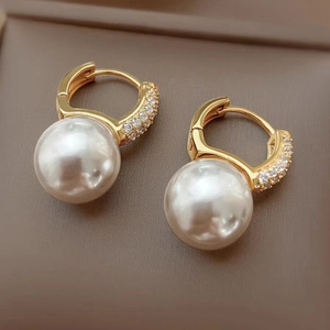 Detail of gold pearl earrings featuring micro-pave zircons and large white pearls