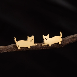 Minimalist cute cat-shaped gold stud earrings displayed on a dark wooden branch